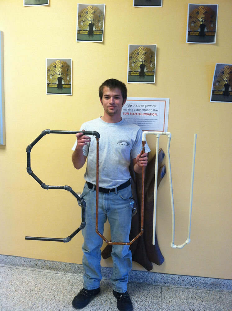 2013 HVAC student Cody Weaver poses with his creation, made out various piping materials.